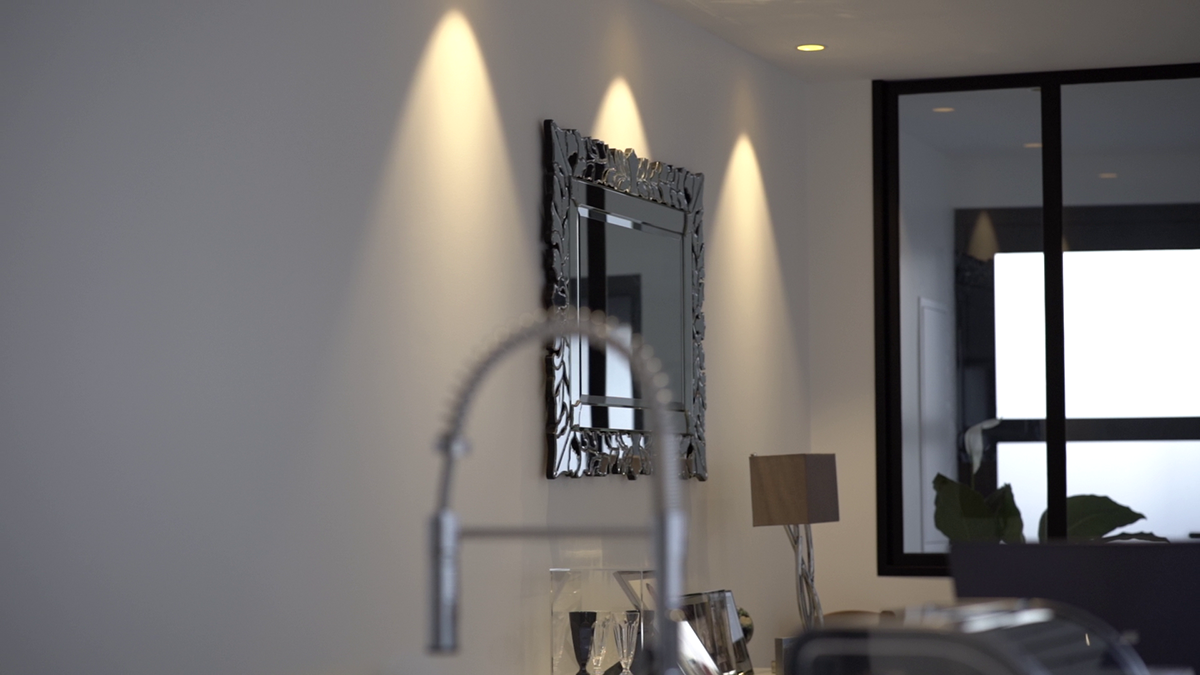 éclairage mural d'une cuisine autour d'un miroir, robinet flouté en premier plan