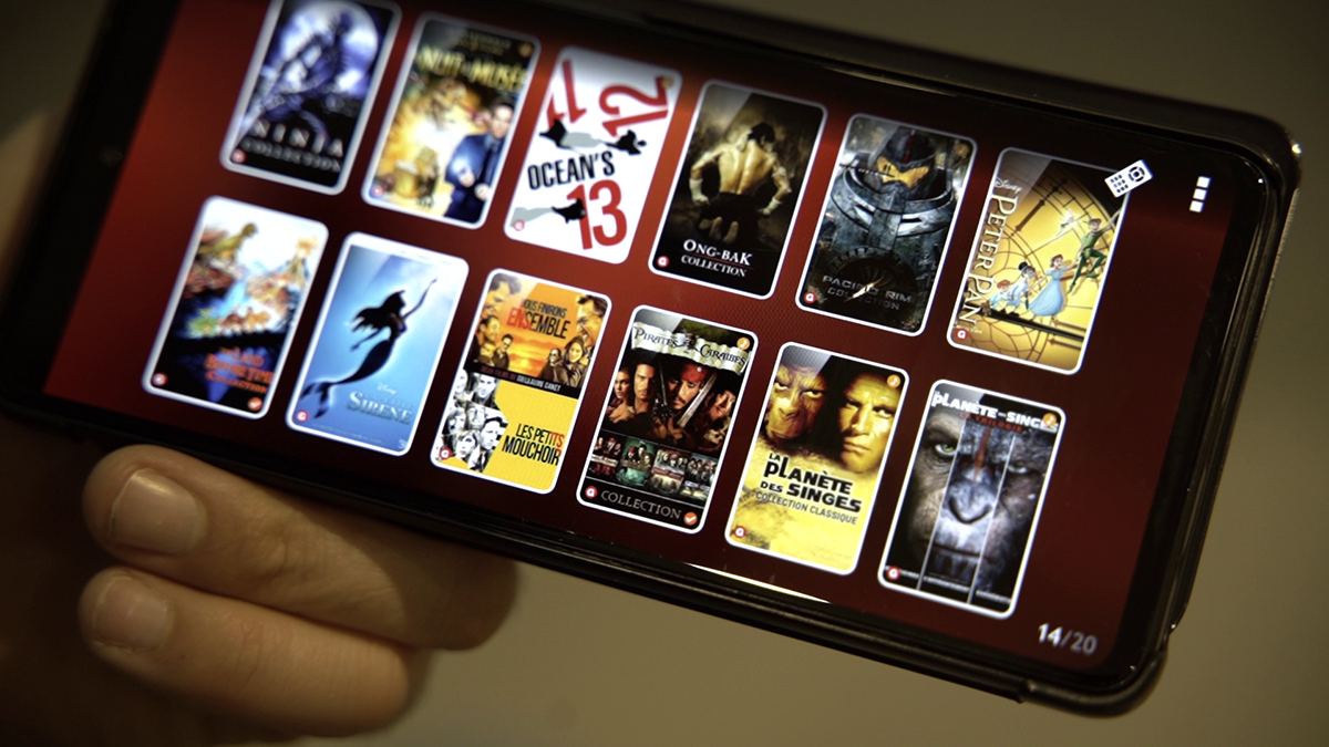smartphone tenu en main affichant une liste de films à envoyer sur une télévision connectée