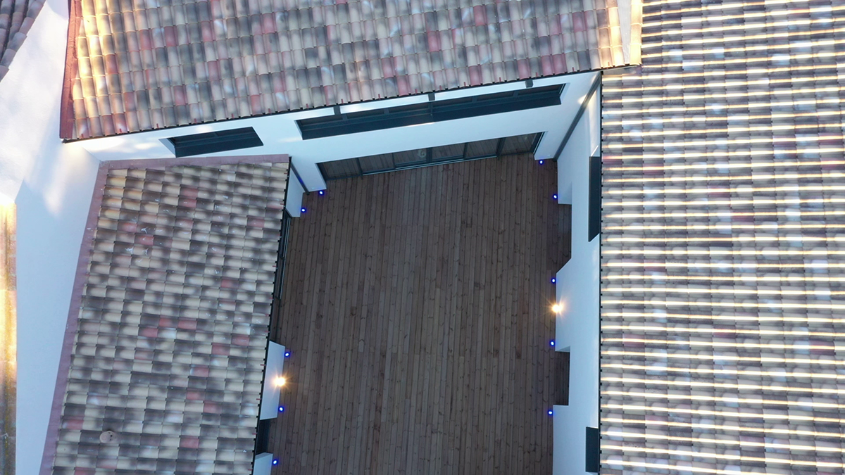 vue d'avion du toit d'une maison et de sa court intérieure avec spots d'éclairage allumés