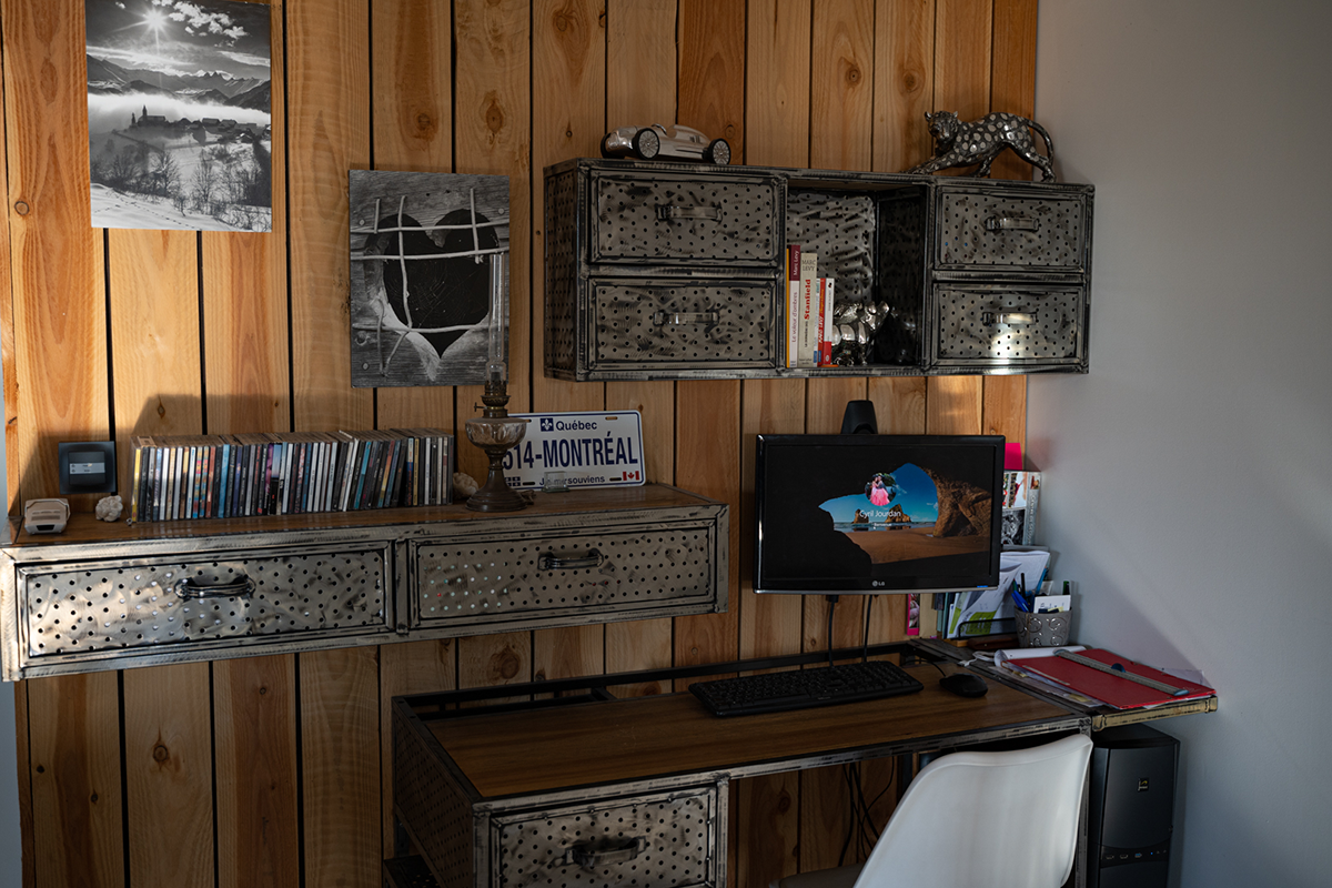 bureau, mur du fond en planches de bois, étagères et bureau en bois et métal, ordinateur avec écran accroché sur le mur en bois