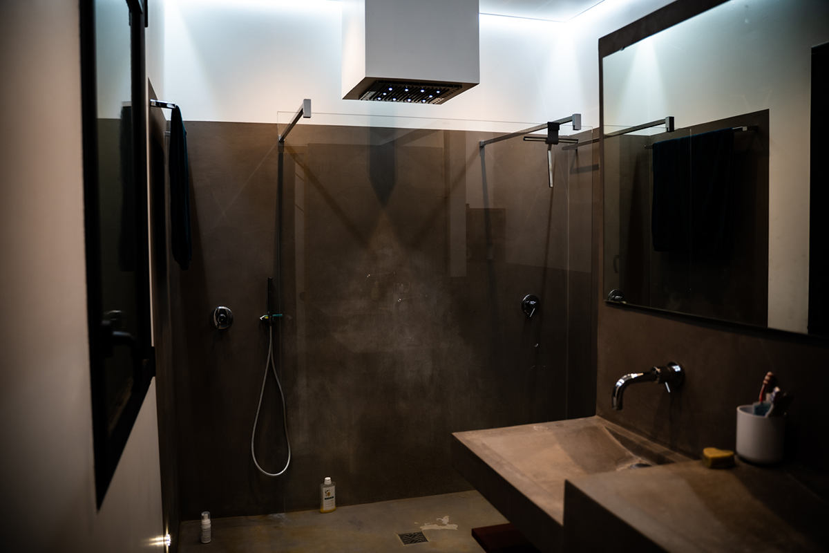 salle de bain, deux douches à l'italienne, évier en pierre de couleur marron, éclairage sur la longueur des côtés du plafond