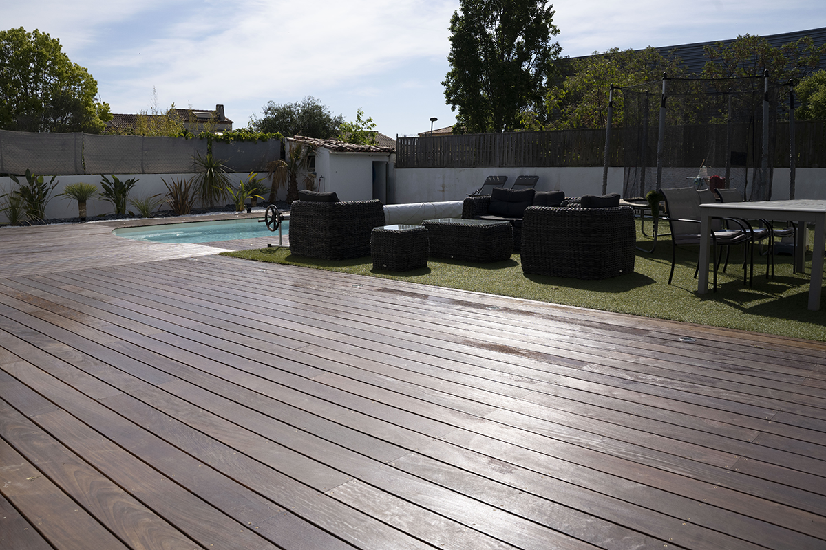 terrasse extérieure de maison avec vue sur le gazon avec table et chaises et canapé de jardin, piscine en arrière plan