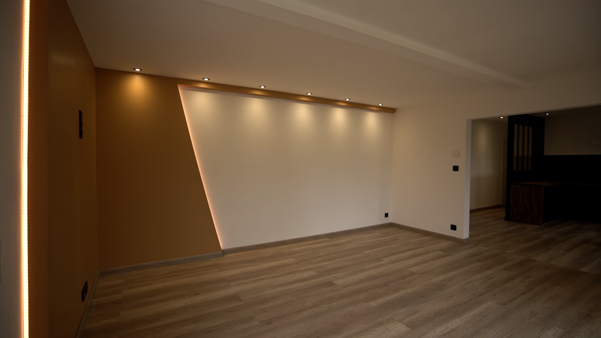 éclairage de salon par des spots encastrés au bord de plafond et bandes de LED verticales